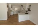 Open kitchen with white cabinets, quartz countertops, stainless sink and wood floors at 3504 Portersfield Rd, Orlando, FL 32808