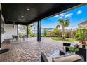A spacious, covered patio with brick pavers, outdoor seating, and a view of the landscaped backyard at 6439 Trailblaze Bnd, St Cloud, FL 34771