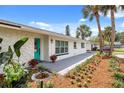 Close-up of the front entrance with a gray walkway, colorful flowers, and a bright turquoise door at 7320 Fieldcrest Ave, Winter Park, FL 32792