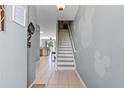 Bright foyer with tile flooring, staircase, and wall decor leading to the living spaces at 7666 Sir Kaufmann Ct, Kissimmee, FL 34747