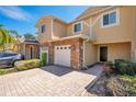 Townhouse exterior featuring stone accents, a two-car garage, and a brick-paved driveway at 10124 Shadow Leaf Ct, Orlando, FL 32825