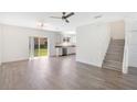 Open-concept living area with wood-look flooring, stairs, and sliding doors to the backyard at 10124 Shadow Leaf Ct, Orlando, FL 32825
