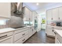 Well-appointed kitchen featuring stainless steel appliances, white cabinets, stylish backsplash, and wood-look tile flooring at 10255 Beechwood Ln, Orlando, FL 32832