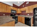 Cozy kitchen with stainless steel appliances, tile flooring, black microwave, and wooden cabinets at 205 Twisting Trl, Orlando, FL 32825