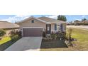 Inviting single-story home featuring a well-maintained lawn, two-car garage, and cozy front garden at 2451 Spring Breeze Dr, Leesburg, FL 34748