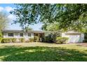 Charming single-story home featuring a manicured lawn, brick accents, attached two-car garage, and mature trees at 2545 Dellwood Dr, Orlando, FL 32806