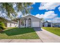 Well-maintained single-Gathering home boasts a pristine lawn, tree coverage, and attached two-car garage at 3063 Jon Jon Ct, Orlando, FL 32822