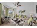 Bright living room featuring a ceiling fan, neutral furniture, decorative pillows, and natural light from the window at 3893 Wind Dancer Cir, St Cloud, FL 34772