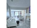 Spacious living room featuring modern white furniture and an open floorplan leading to the dining area at 4730 Capital Blvd, St Cloud, FL 34769