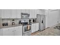 Bright kitchen features white cabinets, stainless steel appliances, and granite countertops at 7012 Oakwood St, Davenport, FL 33837
