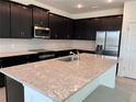Modern kitchen featuring a large island with granite countertops and stainless steel appliances at 725 Ginger Dr, Haines City, FL 33844