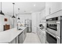 Modern kitchen featuring white cabinets, stainless steel appliances, a center island, and stylish pendant lighting at 7633 Agrigento St, Clermont, FL 34714