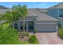 Beautiful single-story home featuring a brick-paved driveway, two-car garage, and lush landscaping, seen from an aerial perspective at 861 Grazie Loop, Davenport, FL 33837