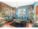 Living room showcasing hardwood floors, blue walls, modern furniture, and natural light from the window at 10321 Pebblestone Ct, Leesburg, FL 34788