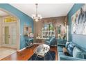 Living room featuring hardwood floors, blue walls, modern furniture, and a decorative chandelier at 10321 Pebblestone Ct, Leesburg, FL 34788