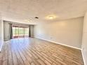 Bright, airy living room with modern wood-look tile floors and sliding glass doors leading to outdoor space at 1232 Roma Ct, Orlando, FL 32825