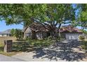 Brick home featuring a well-manicured lawn and a large tree providing substantial shade coverage at 20705 Nettleton St, Orlando, FL 32833
