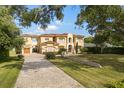 Expansive Mediterranean-style home with a brick driveway, porte-cochere, and lush landscaping at 225 Magnolia St, Windermere, FL 34786