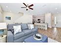 Open-concept living room with a stylish sofa, nearby kitchen with bar seating, and wood-look flooring at 3192 Caribbean Soul Dr, Kissimmee, FL 34747