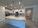 Open kitchen with a granite island, stainless steel appliances, and white cabinetry at 3990 Lana Ave, Davenport, FL 33897
