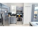 Galley kitchen with stainless steel appliances, granite countertops, and white tile flooring at 4720 Hemingway House St, Kissimmee, FL 34746