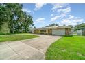 Ranch style home featuring a stone facade, two-car garage, lush lawn and lengthy drive at 690 S Lakemont Ave, Winter Park, FL 32792