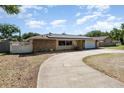 Charming single-story home with solar panels, a stone facade, two-car garage, and a curved driveway at 690 S Lakemont Ave, Winter Park, FL 32792