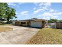 Inviting single-story home featuring solar panels, a stone facade, a two-car garage and a curved driveway at 690 S Lakemont Ave, Winter Park, FL 32792