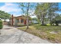 Landscaped front yard and charming single-story home with a red brick chimney and ample sunlight at 712 Baffie Ave, Winter Park, FL 32789