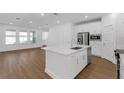 Open-concept kitchen with stainless steel appliances and white cabinetry that flows seamlessly into the living area at 13532 Autumn Harvest Ave, Winter Garden, FL 34787