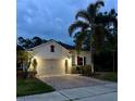 Well-lit home exterior at dusk featuring a two-car garage and tropical landscaping at 2301 Avellino Ave, St Cloud, FL 34771