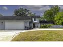 View of the light grey exterior with attached garage and a lush lawn at 4174 Fallwood Cir, Orlando, FL 32812