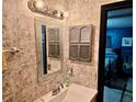 Compact bathroom with vintage wallpaper, decorative mirror and vanity, adjacent bedroom entry at 527 Leland Dr, Deltona, FL 32725