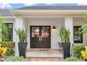 Inviting front entrance featuring double doors flanked by tall snake plants and a cozy seating area at 7455 Sparkling Lake Rd, Orlando, FL 32819