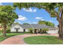 Charming home featuring mature trees, manicured landscaping, circular driveway and elegant architecture at 7455 Sparkling Lake Rd, Orlando, FL 32819