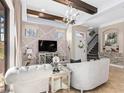 Sophisticated living room features a stone accent wall, beamed ceiling and modern decor, complemented by ample natural light at 10765 Village Lake Rd, Windermere, FL 34786