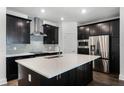 Modern kitchen features stainless appliances, dark cabinetry, and a central island with quartz countertop at 13536 Autumn Harvest Ave, Winter Garden, FL 34787