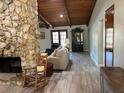 Inviting living room featuring a stone fireplace, wood ceiling, and neutral-toned sofa at 1500 Markham Woods Rd, Longwood, FL 32779