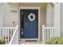 Inviting front door with sidelight, wreath, and bench on a covered front porch at 15456 Blackbead St, Winter Garden, FL 34787