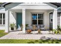 Inviting covered front porch with stylish seating, lush landscaping, and a bright turquoise front door at 1806 Paloma Ave, Sanford, FL 32771