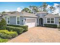 Charming exterior view of a grey home featuring an arched entryway and a brick paver driveway at 231 Cherokee Hill Ct, Deland, FL 32724