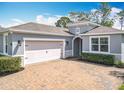 Charming exterior view of a grey home featuring an arched entryway and a brick paver driveway at 231 Cherokee Hill Ct, Deland, FL 32724