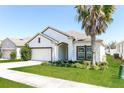 Stylish single-story home with a manicured lawn and a white exterior and a neatly trimmed palm tree at 2430 Sanderling St, Haines City, FL 33844