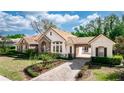 A side view of a single-story home featuring stone accents, a tile roof, a porte-cochere and driveway at 25813 Feather Ridge Ln, Sorrento, FL 32776