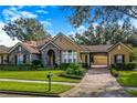 Charming single-story home featuring stone accents, porte-cochere, manicured landscaping, and brick paved driveway at 25813 Feather Ridge Ln, Sorrento, FL 32776