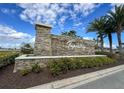 Stone community sign with lush landscaping and palm trees in a well-kept neighborhood at 2694 Giardino Loop, Kissimmee, FL 34741
