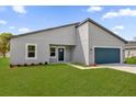 Contemporary one-story home featuring blue garage door, sleek facade, and green lawn at 3984 Sw 151St St, Ocala, FL 34473