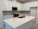 Bright kitchen with white cabinetry, stainless steel appliances, island with quartz countertop, and subway tile backsplash at 618 Duke Dr, Haines City, FL 33844