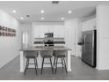 Bright kitchen features white cabinets, a kitchen island with barstool seating, and stainless steel appliances at 660 Silver Palm Dr, Haines City, FL 33844