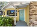 Close-up of the home's entrance with a teal door, yellow siding, and brick accents at 926 Mayfair Cir, Orlando, FL 32803